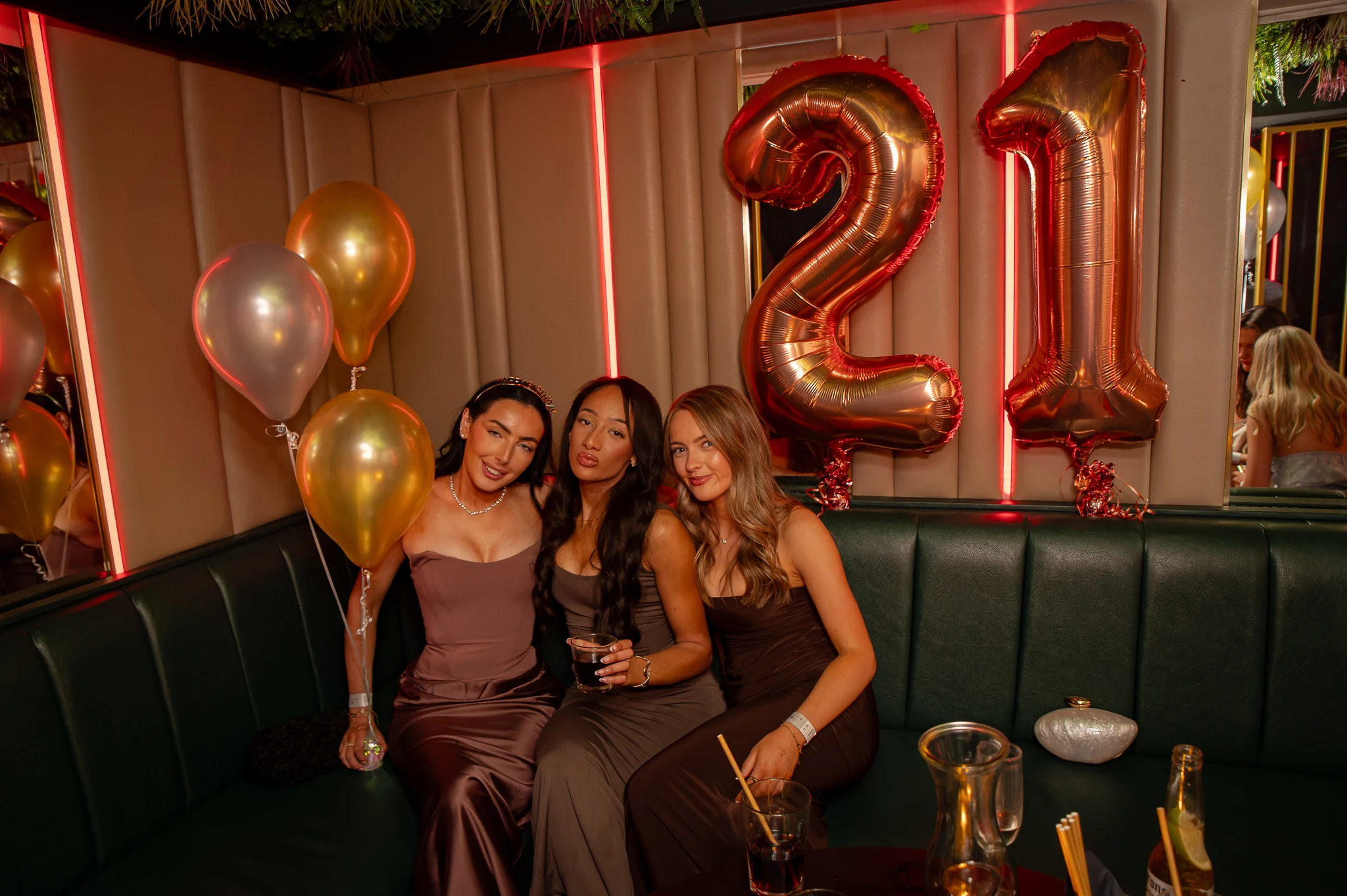 A 21st birthday celebrated in a club booth with gold balloons