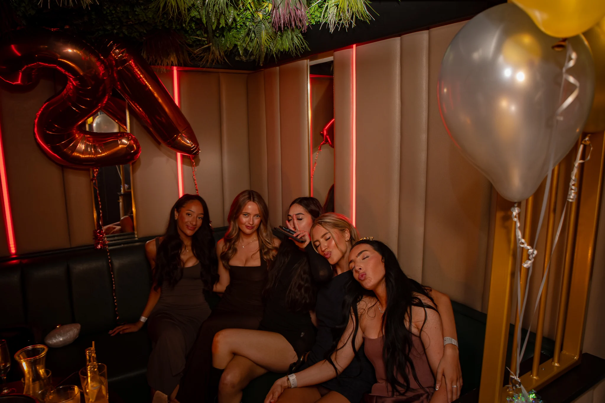 A 21st birthday group in a VIP booth with balloons