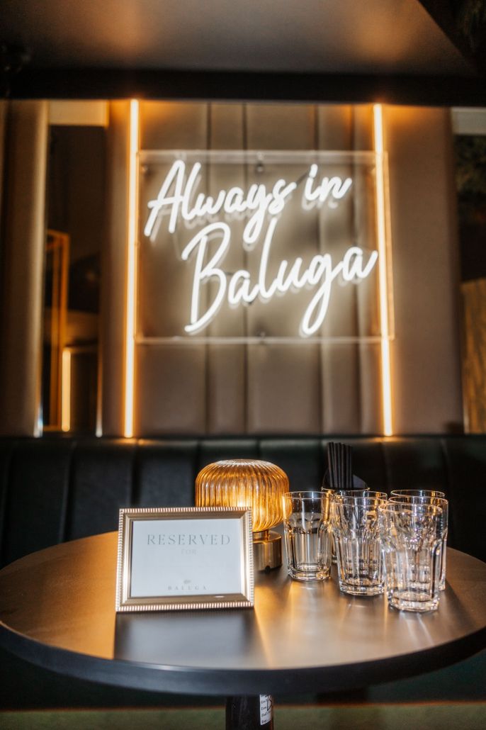 A reserved table beneath the Always in Baluga neon
